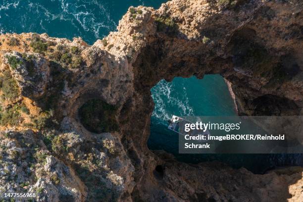 boat going into a cave at praia da marinha, rocks and cliffs, steep coast in the algarve, portugal - algarve portugal stock-grafiken, -clipart, -cartoons und -symbole