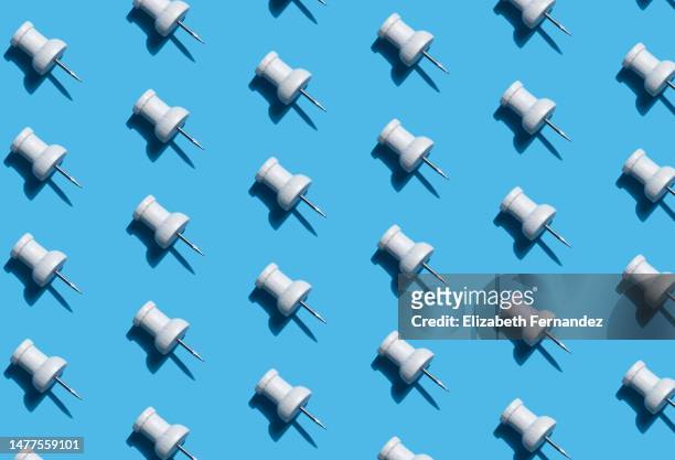 push pins in a repeating pattern on blue background - push pin stockfoto's en -beelden