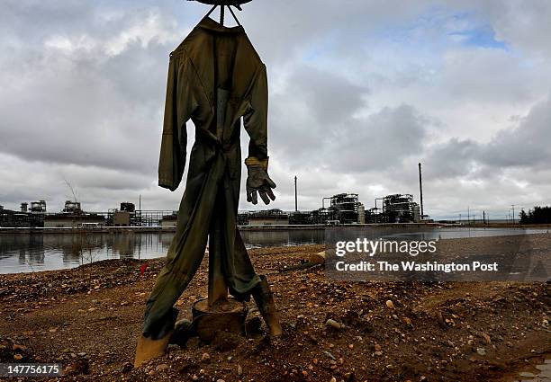 Crude scarecrow is used to thwart birds from landing in the oil residue floating on top of a tailings pond at the Syncrude oil processing facility.