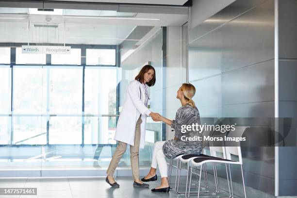 woman shaking hands with doctor in waiting room - assistenza ambulatoriale foto e immagini stock