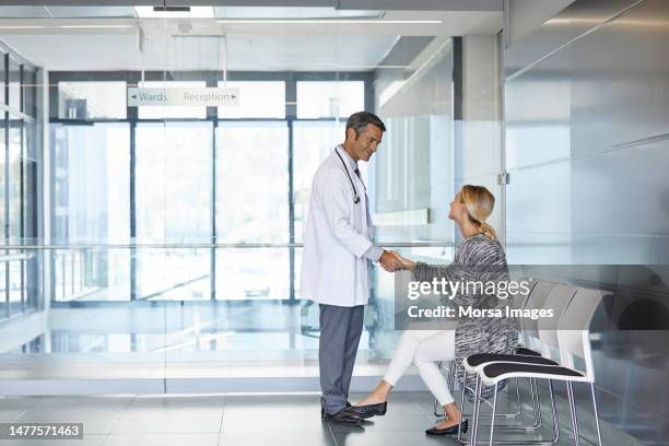 woman shaking hands with doctor in waiting room - doctor stethoscope patient whole body stock pictures, royalty-free photos & images