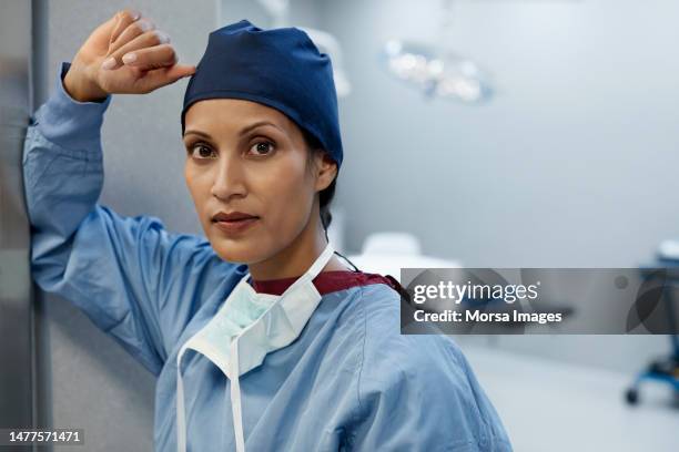 portrait of surgeon with hand raised at hospital - chirurgenkappe stock-fotos und bilder