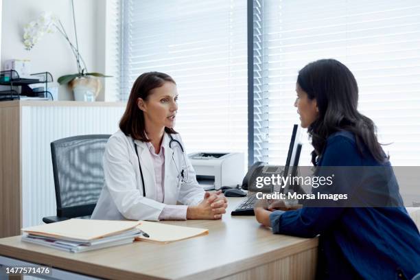 doctor talking with female patient in clinic - medische procedure stockfoto's en -beelden