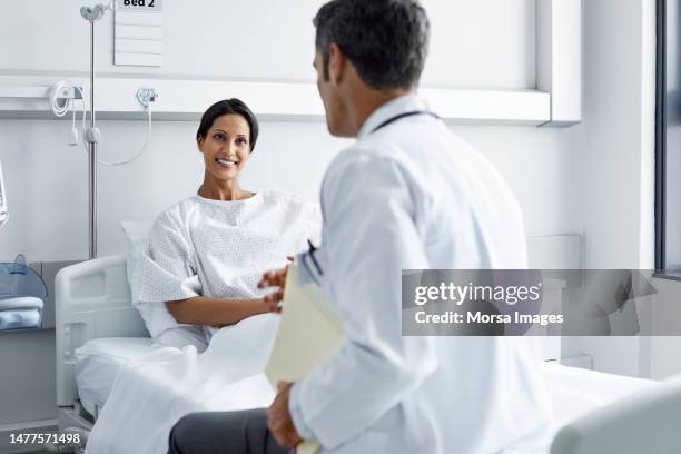 smiling patient looking at doctor sitting on bed - patientkontakt bildbanksfoton och bilder