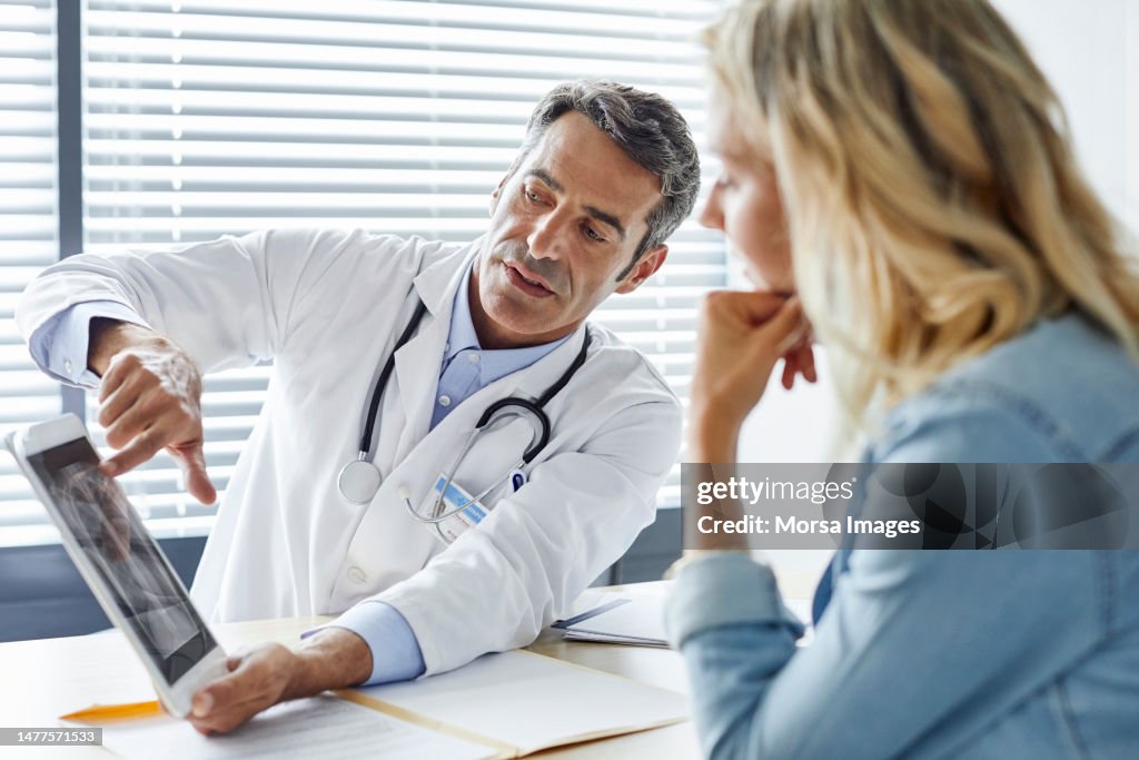 Doctor showing digital tablet to woman in hospital
