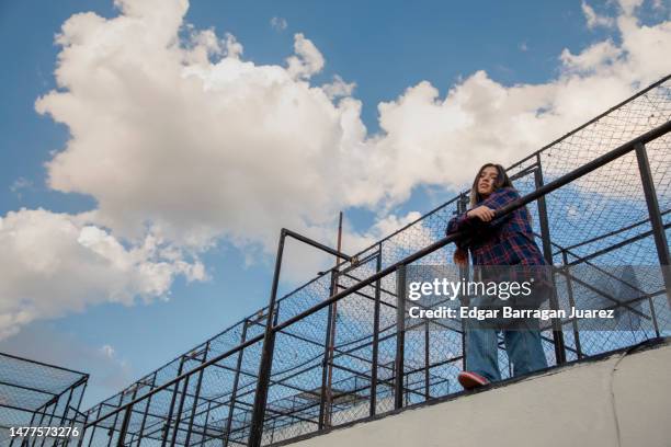 joven mujer mexicana en la azotea de una casa, apoyada en la barda mirando a camara - mujer mexicana stock pictures, royalty-free photos & images