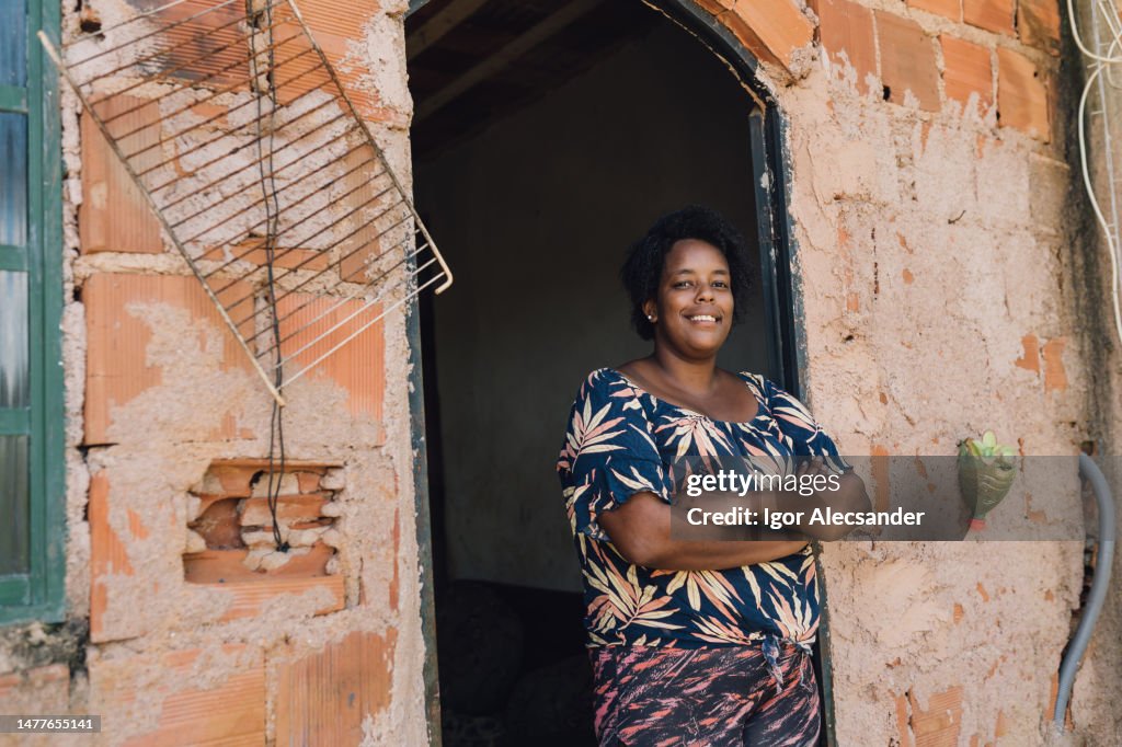 Smiling woman in front of her humble home