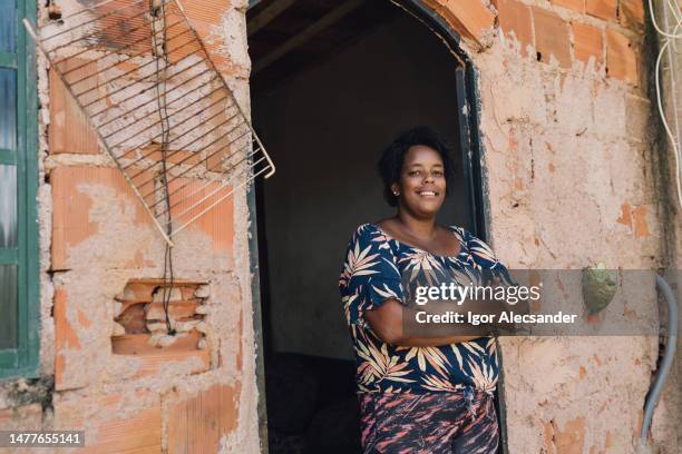 smiling woman in front of her humble home - starving woman stock pictures, royalty-free photos & images