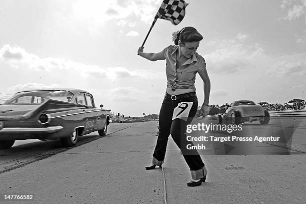 Starter girl starts a race over a 150 meter long short sprint track. Many thousand oldtimer and rock and roll enthusiasts attend the 'Roadrunners...