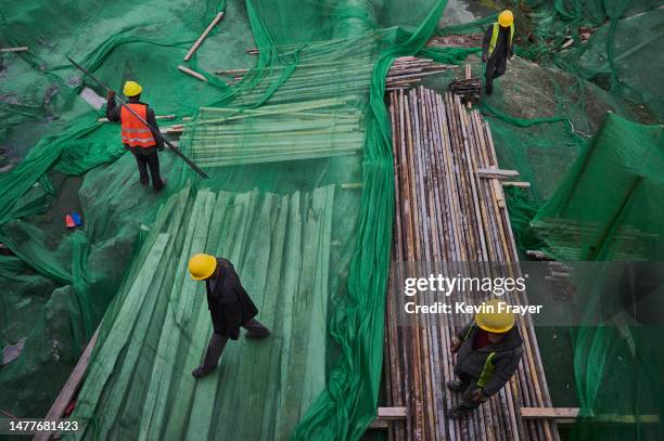 Construction workers walk on fabric placed to prevent dust and debris from blowing at a construction site on March 28, 2023 in Beijing, China.