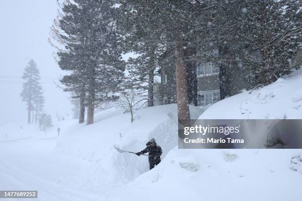 Worker shovels a walkway as snow falls in the Sierra Nevada mountains from yet another storm system which is bringing heavy snow to higher elevations...