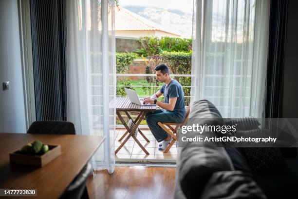 man working on laptop and relaxing on balcony. - ver stockfoto's en -beelden