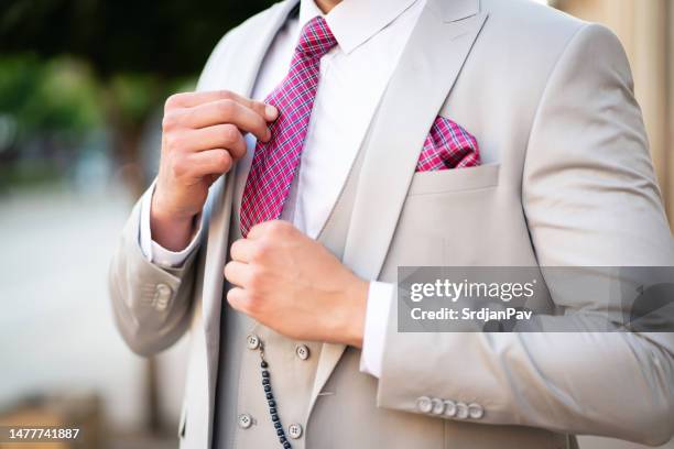 unrecognizable man adjusting his tie, while wearing suit - adjusting suit stock pictures, royalty-free photos & images