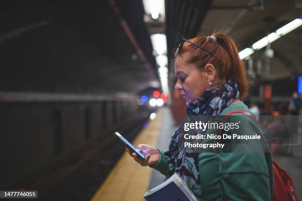 woman waiting subway train and using smartphone, new york city, usa - station de vacances 個照片及圖片檔