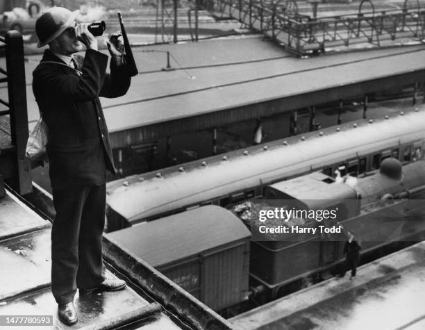 Civil defence firewatcher of the Air Raid Precaution of the London North Eastern Railway scans the sky with binoculars searching for German Luftwaffe...