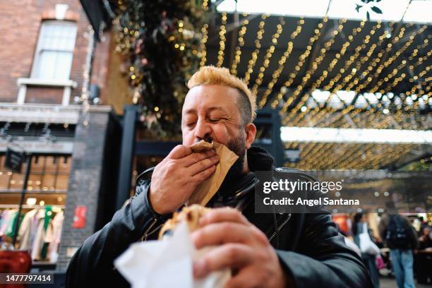 man spontaneously cleans mouth with napkin while enjoying food market fare. - munchies stock pictures, royalty-free photos & images