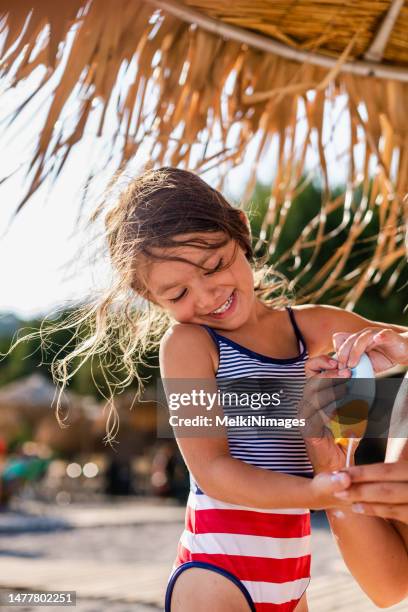 mother and child putting sunprotection together - putting lotion stock pictures, royalty-free photos & images