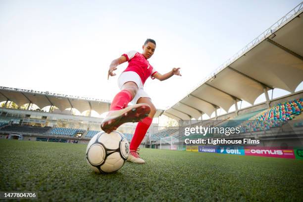 low angle photograph of active woman soccer player reaching leg towards ball - stadium stock pictures, royalty-free photos & images