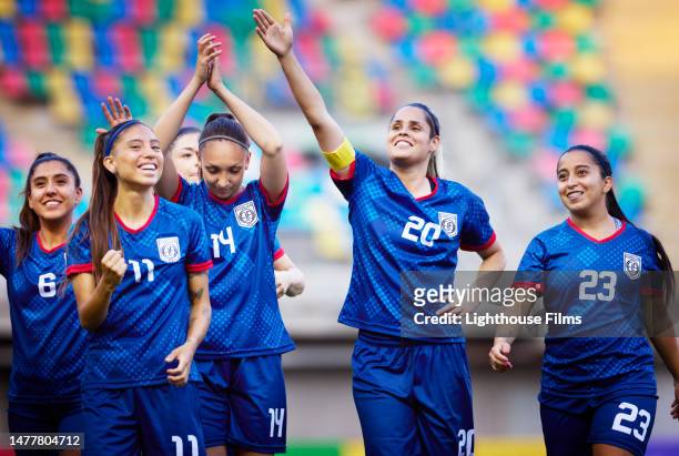 team of professional women's soccer players raise their arms to the crowd and celebrate - team captain fotografías e imágenes de stock