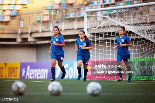 three athletic women footballers jog during warm-ups before a competition - sports drill stock-fotos und bilder