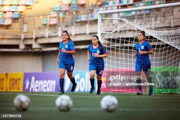 three athletic women footballers jog during warm-ups before a competition - sports drill stock pictures, royalty-free photos & images