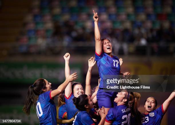 celebrating women soccer players raise up their star player after winning the final in an international cup - competición de fútbol fotografías e imágenes de stock