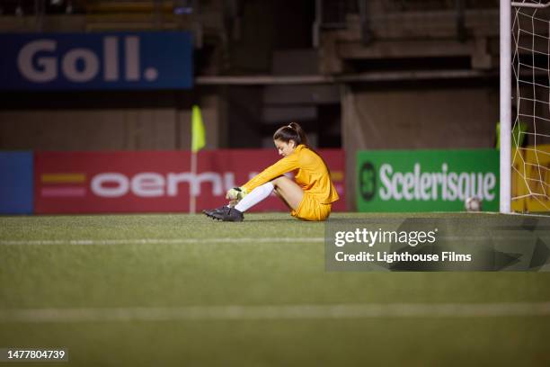 goalie disappointingly sits down on soccer field after losing a match - woman goalie stock pictures, royalty-free photos & images