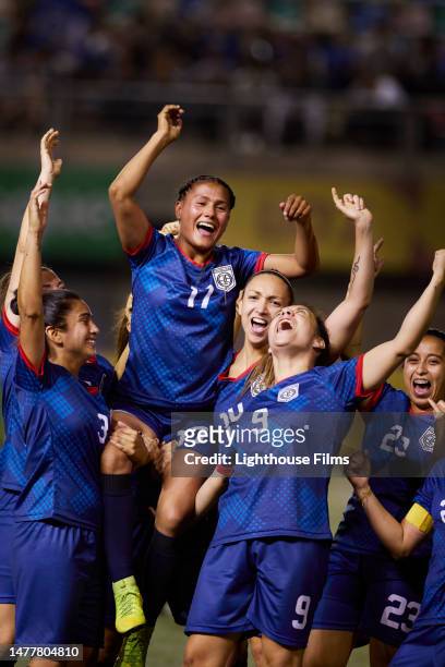 passionate team of soccer players lift up their star teammate after winning a game - international team soccer stock-fotos und bilder