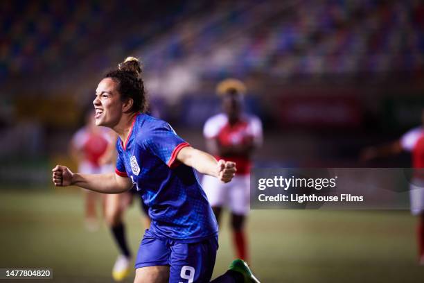 ecstatic female soccer player pumps her firsts and runs to her teammates as she celebrates scoring a goal from a penalty kick - athlete stock pictures, royalty-free photos & images