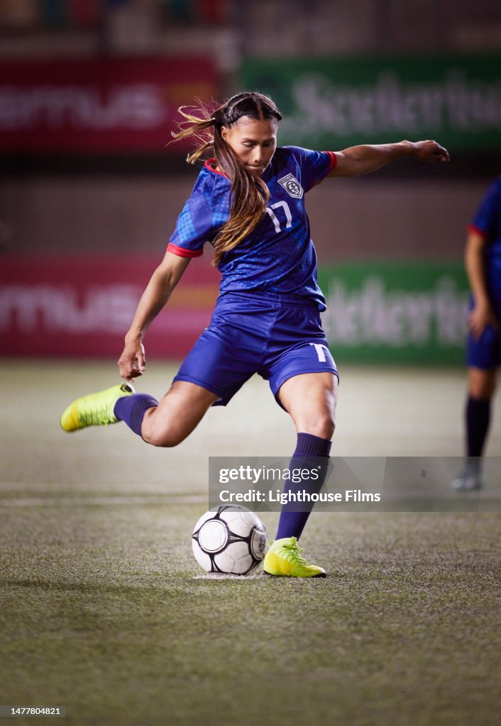 Focused female soccer player wins her shooting leg back to take a penalty kick