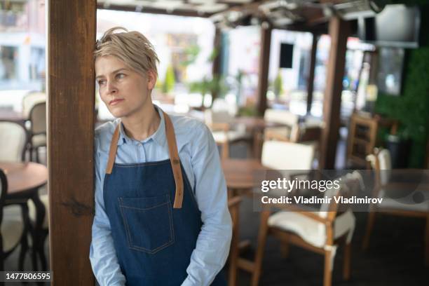 portrait of a restaurant manager standing distraught in the middle of her empty restaurant - overworked waitress stock pictures, royalty-free photos & images