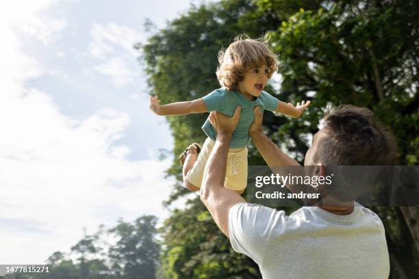 happy father playing with his son at the park lifting him from the ground - child picking up toys stock pictures, royalty-free photos & images