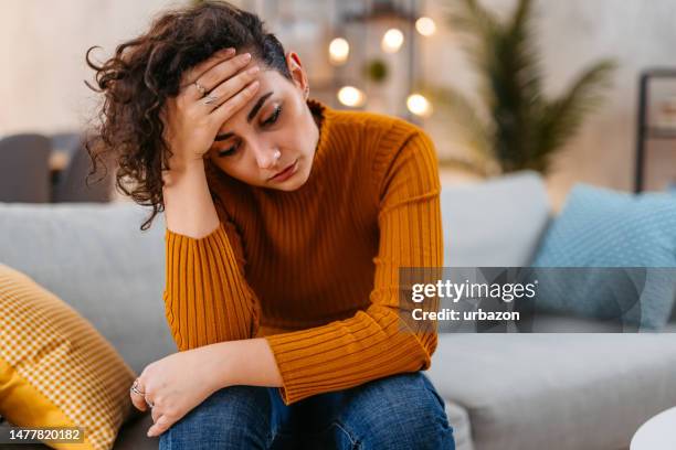 giovane donna triste che si siede a casa sul divano di notte - one young woman only foto e immagini stock