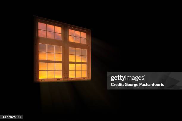 dark room with a window and a view of the sunset clouds - breaking window stockfoto's en -beelden