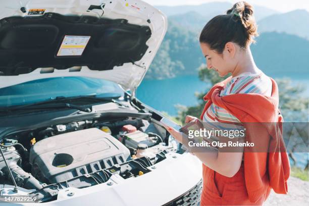 lost in wilderness area without signal with broken car. rearview brunette woman using smartphone, looking for signal to call rescue service - remote location cell phone stock pictures, royalty-free photos & images