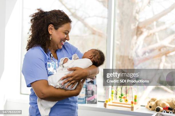 女性看護師は笑顔で赤ちゃんを見る - baby　smile ストックフォトと画像