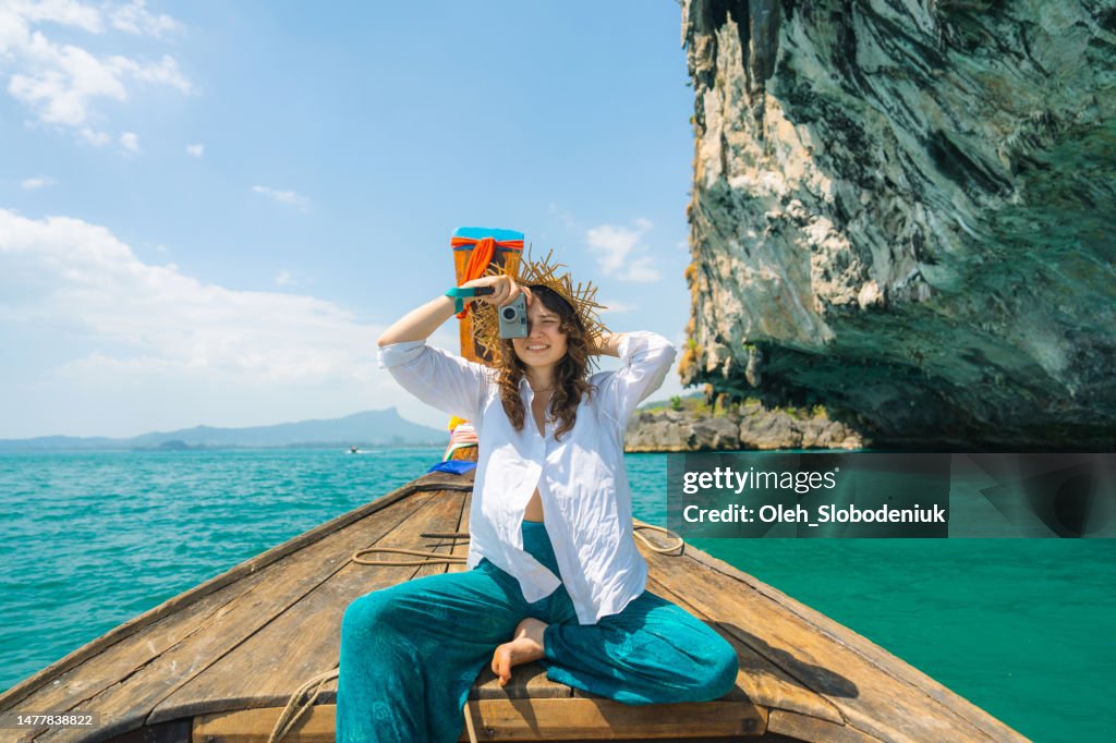 Femme joyeuse voyageant avec un bateau-taxi thaïlandais et photographiant avec un appareil photo point and shoot