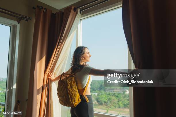 mulher que entra em seu quarto no hotel e olha através da janela sobre a vista das selvas - hóspede - fotografias e filmes do acervo