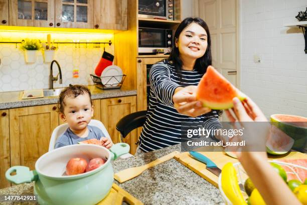 asian family eating fruit at home - boys long hair cuts stock pictures, royalty-free photos & images