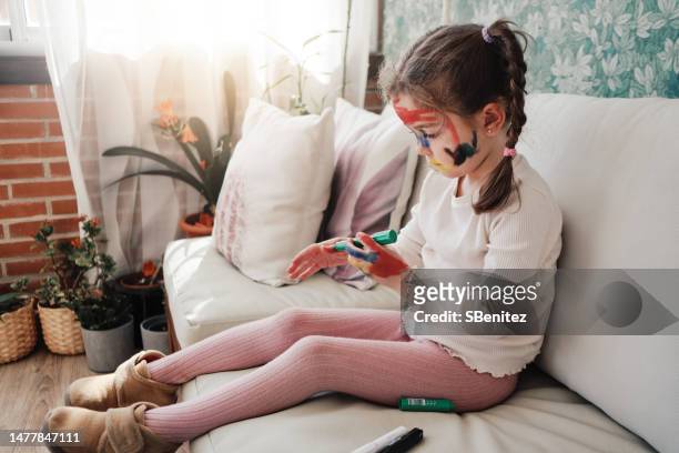 little girl painting her hand green with a paint - kids makeup face stock-fotos und bilder