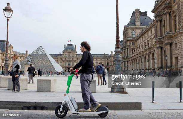 Man rides a Lime electric scooter in front of the Louvre pyramid and the Louvre museum on March 29, 2023 in Paris, France. The Mayor of Paris, Anne...