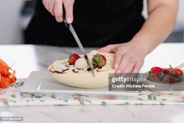 woman cutting a homemade chocolate easter egg - pascoa stockfoto's en -beelden