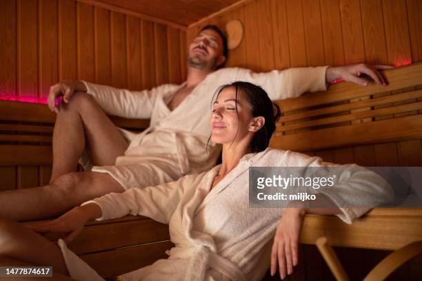 mid adult couple enjoying time in sauna - sauna wellness stock pictures, royalty-free photos & images