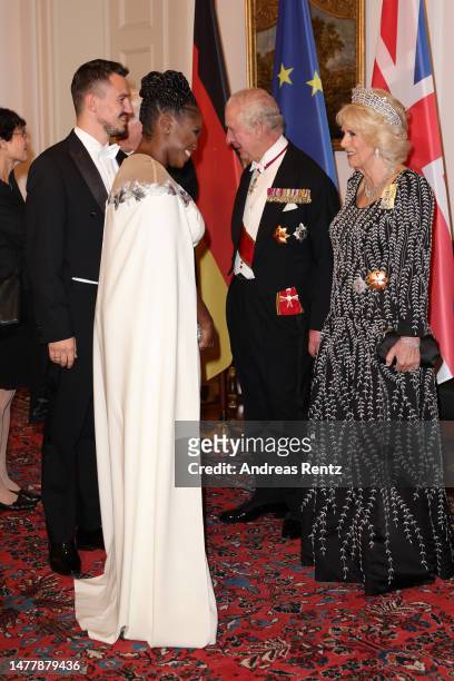 King Charles III and Camilla, Queen Consort greet Evgenij Voznyuk and Motsi Mabuse during a state banquet defilee at Schloss Bellevue presidential...