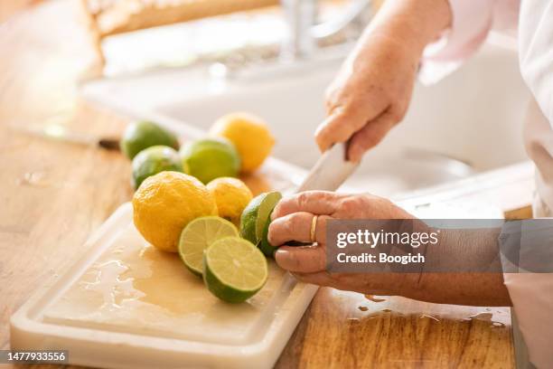 senior woman slicing lemons and limes on a cutting board - lime stock pictures, royalty-free photos & images