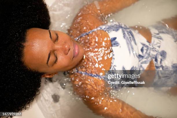 young woman smiling while lying in a relaxing hot tube - hydrotherapy stock pictures, royalty-free photos & images