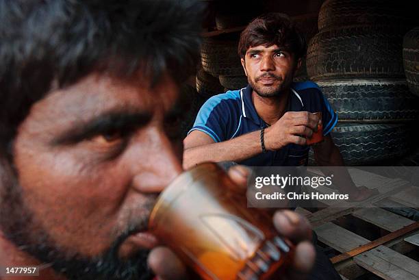 Indian dock workers drink tea during a break after unloading tires October 15, 2002 in Dubai, United Arab Emirates. Dubai is quickly becoming the New...