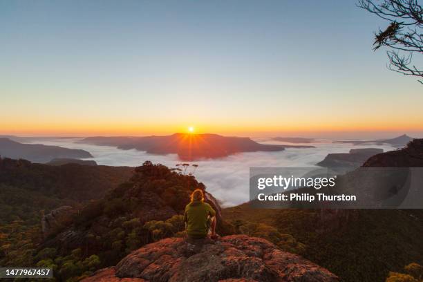 young man enjoying the view on top of a mountain at sunrise - top of the mountain australia stock pictures, royalty-free photos & images