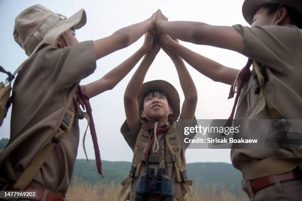 three boy scouts in camp with backpacks holding hands on the mountai - boy scout camping stockfoto's en -beelden