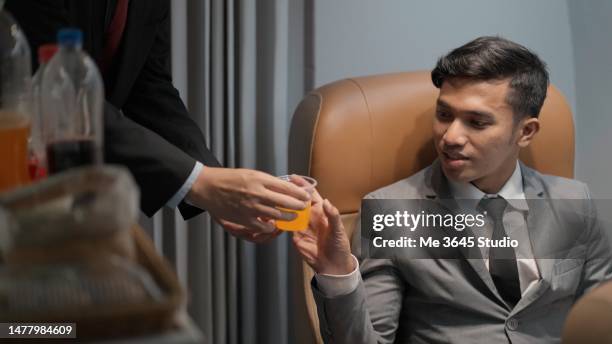 lifestyle of tourists traveling on a plane.air steward takes care of passengers on the plane - anzug ausland stock-fotos und bilder